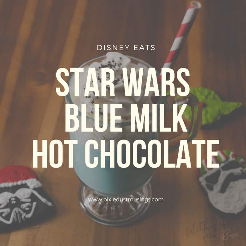 a tall clear glass with blue milk hot chocolate surrounded by Christmas star wars cookies